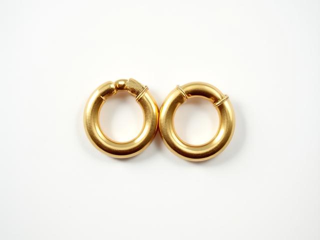 Minimalist gold hoop earrings against a sustainable fabric background